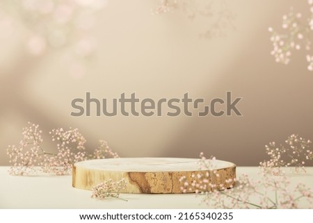 Empty round wooden podium for product presentation, pink gypsophila flowers on beige background. Natural materials background for cosmetic advertising with cylinder shape showcase. Mockup concept.
