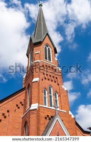 Beautiful brick church in small Midwest town with blue skies and clouds in the background.