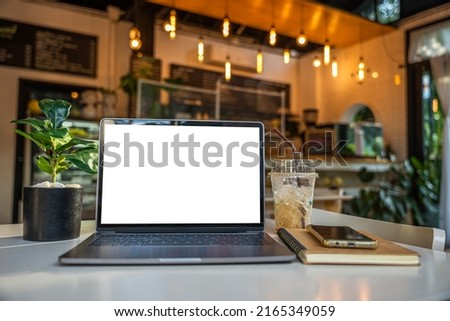 Mockup of laptop computer with empty screen with notebook,ice coffee and smartphone on table side the window in the coffee shop at the cafe,White screen