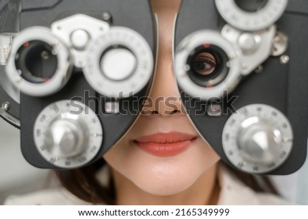 A Young female customer being examined visual test using Bifocal Optometry eyesight measurement device by ophthalmologist in optical center, eye care concept. Royalty-Free Stock Photo #2165349999