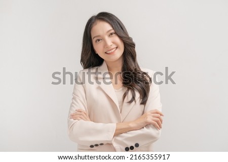 Smiling positive, attractive asian young woman, girl in beige suit formal dress, portrait elegant of pretty with long black hair, feeling happy looking at camera standing isolated on white background. Royalty-Free Stock Photo #2165355917