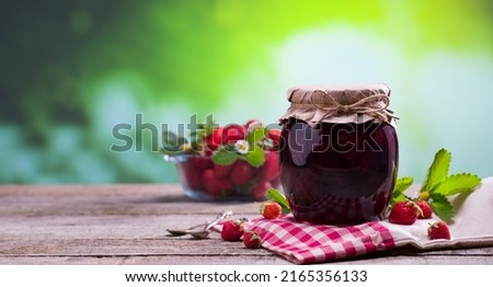 Jar of strawberry jam on wooden table with natural background at sunset. Delicious breakfast natural strawberry jam and fresh strawberries.