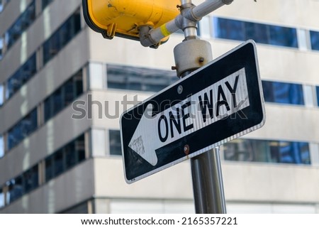 One Way sign on a city street with building