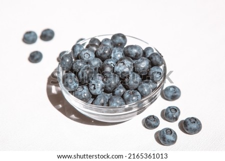 Fresh blueberries in bowl and heap of berries on white table, healthy summer food