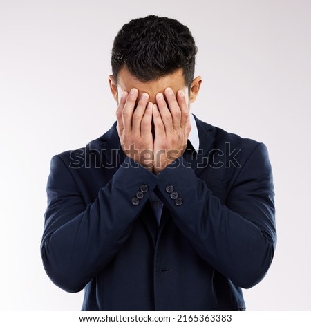 Somebody save me from this misery. Studio shot of a young businessman covering his face against a white background.