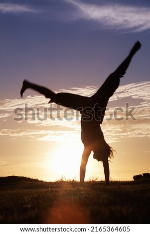 Handstand. Silhouette of a woman doing handstand at sunrise. Royalty-Free Stock Photo #2165364605