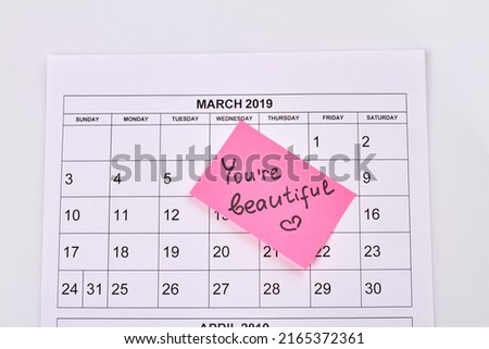 March calendar and sticker note with you are beautiful handwriting. Top view flat lay.