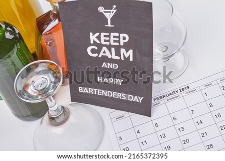 Bartenders day concept. February calendar and many alcoholic drinks. Top view bottles with various booze.