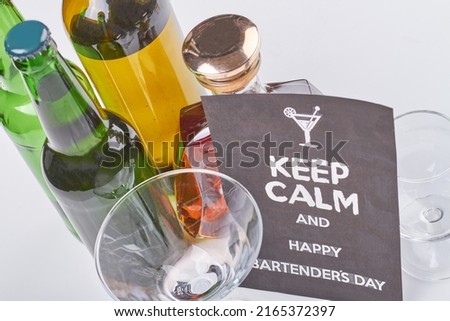 Keep calm and happy bartenders day. Many alcohol bottles on white background. Top view alcoholic drinks.