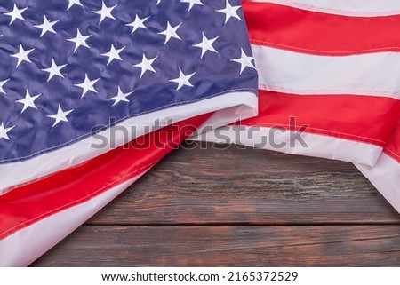 Close-up large fabric United States flag on wood. USA banner with stripes and stars.