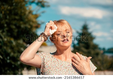 Woman feeling bad pain, heat, woman with heatstroke. Having sunstroke at summer hot weather. Mature Female under sunshine suffering from Headache. Person holds paper tissue on head Royalty-Free Stock Photo #2165386657