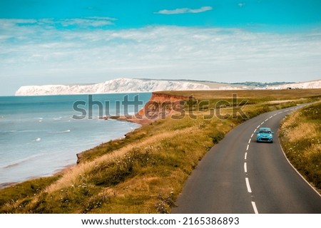 Aerial panoramic view of road with blue car on it with the Needles and sea view. The Isle of WIght, UK Royalty-Free Stock Photo #2165386893