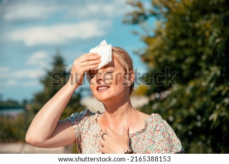 Portrait of Blonde pretty Woman having hot flash and sweating on sun heat at Summer day outdoors Royalty-Free Stock Photo #2165388153