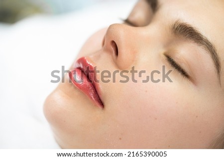 Closeup of female lips after permanent makeup lip blushing procedure Royalty-Free Stock Photo #2165390005
