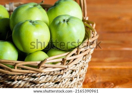 Composition with juicy green apples in wicker basket on table. Space for text