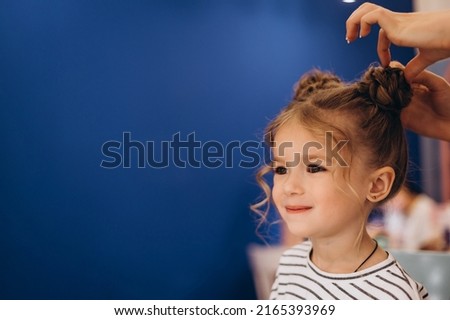 Portrait of a little beautiful girl with a stylish hairstyle in a beauty salon. The process of making a child's hair