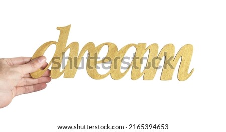 Woman's hand holding a wooden lettering DREAM isolated on white
