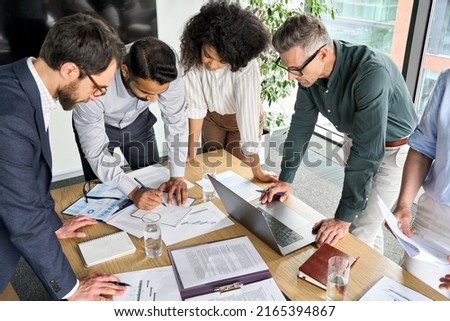 Diverse international executive business people group brainstorming at boardroom meeting table. Multiethnic team discussing project developing business strategy doing paperwork analysis in office. Royalty-Free Stock Photo #2165394867