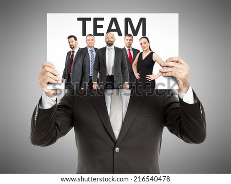 A business man holding a paper in front of his face with a team
