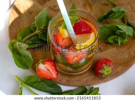 Lemonade with strawberries, mint, lemon on a light background