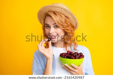 Picking eating cherry fruit. Attractive young woman eating fresh cherry. Healthy summer fruits. Yellow background. Beautiful woman posing with a cherry, girl with cherry promoting. Royalty-Free Stock Photo #2165420987