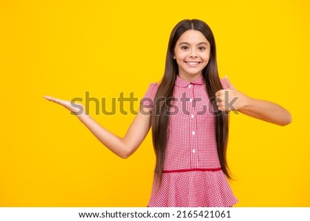 Teenager child pointing to the side with a finger to present a product or idea. Teen girl in casual outfit pointing empty space.