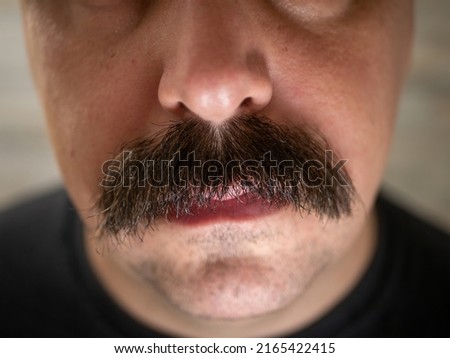 A closeup of a young man's bushy mustache  Royalty-Free Stock Photo #2165422415