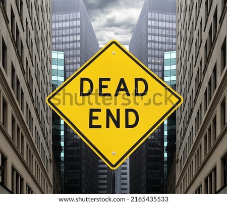Yellow sign symbolizing a dead end against the backdrop of urban development