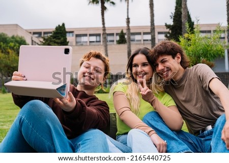 Group of college students taking photos on campus grass