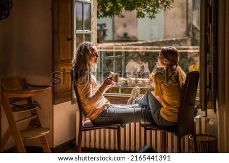 Cheerful teen girl spending time with her parent while drinking tea Royalty-Free Stock Photo #2165441391
