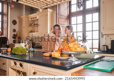 Caucasian woman and her teenage daughter unfolding package with grocery after the shop