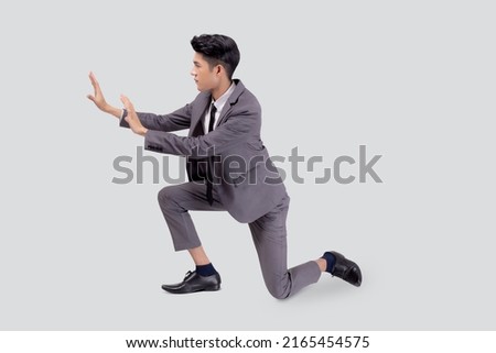 Young asian business man pushing something isolated on white background, businessman strong and with expression difficult, marketing and presentation for success, employee and career job with heavy. Royalty-Free Stock Photo #2165454575