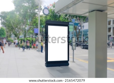 Blank vertical advertising poster banner mockup at bus stop shelter by main road, at city centre; out-of-home OOH billboard media display space. Out-of-focus people at orchard road Royalty-Free Stock Photo #2165472079