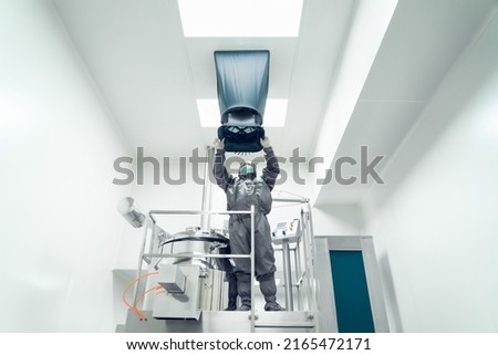 The unidentified operator is using the capture hood balometer to measuring the air velocity and volume of supply air from HVAC system in the clean room. Royalty-Free Stock Photo #2165472171