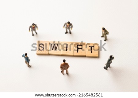 Miniature figures businessman : meeting on swift word by wooden block words on white paper background, swift is abbreviation in concept of international money transfer, and business.