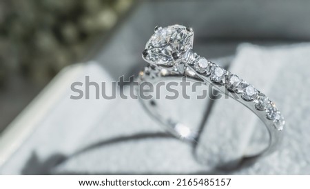 Close up of diamond ring with white flower, sunlight and shadow background. Love, valentine, relationship and wedding concept. Soft and selective focus. Royalty-Free Stock Photo #2165485157
