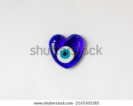 Fridge magnet souvenir in shape of heart from blue evil eye Nazar Boncuk isolated on white background. Love travel to Turkey concept. Top view flat lay close up, copy space Royalty-Free Stock Photo #2165505385