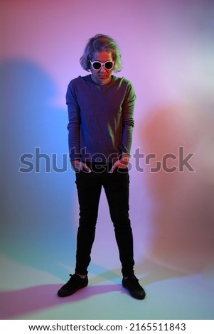 The cool senior Asian man standing on the white background under the color gel lighting. 