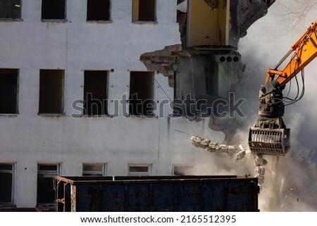 Close up of a bucket of an excavator demolishing an old building. Dangerous demolition works in the city. Photo taken on a sunny day.