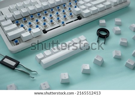 Concept of cleaning disassembled mechanical keyboard game with switch puller and keycaps puller isolated on a white background Royalty-Free Stock Photo #2165512413