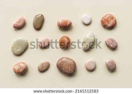 Aesthetic minimal pattern with set of sea pebble stones on beige background. Square composition from natural round smooth stone neutral color. Collection of rocks, summer concept, top view, flat lay