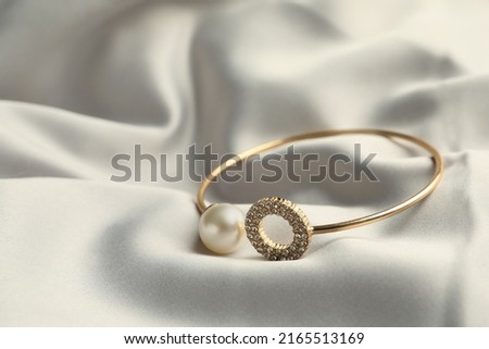Elegant bracelet with pearl on grey silk, closeup Royalty-Free Stock Photo #2165513169