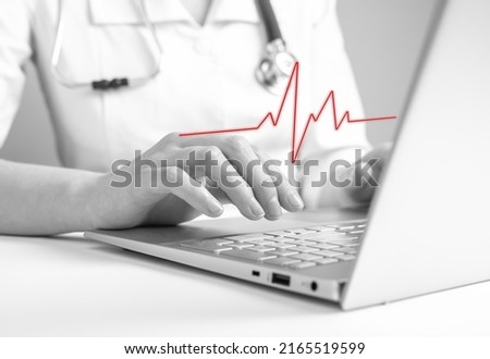 Doctor using laptop for reading electrocardiogram results, checking for signs of heart diseases. Cardiovascular problems, abnormalities detection concept. Black and white. High quality photo