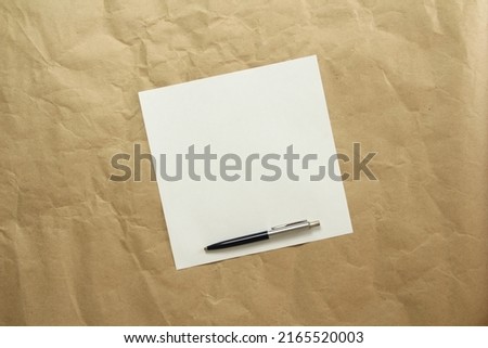 Square white empty sheet of paper with pen on a beige craft paper. Concept of analysis, study, attentive work. Stock photo with empty place for your text and design.