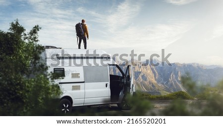 Man on the roof of his camper van Royalty-Free Stock Photo #2165520201