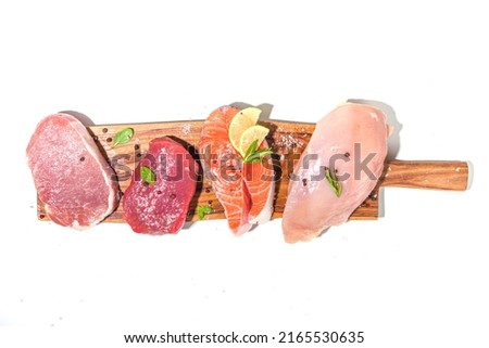 Various natural food, high animal protein sources - pork, beef meat steaks, chicken breast fillet, eggs, salmon fish on white table background top view copy space 