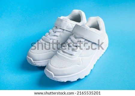 white kid sneakers with velcro on blue background