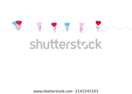 Wooden clothes pins in heart shape patterns hanging on white string isolated on white background , clipping path (pink red blue seven )	