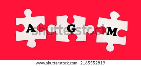 Three white jigsaw puzzles with the text AGM Annual General Meeting on a bright red background.