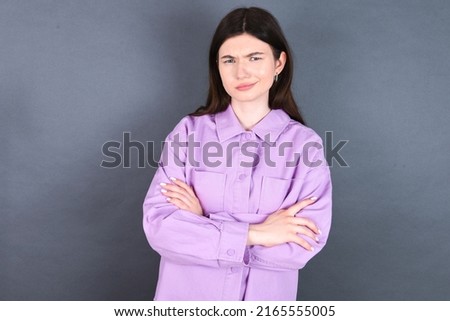 young caucasian woman wearing purple shirt over grey background Pointing down with fingers showing advertisement, surprised face and open mouth